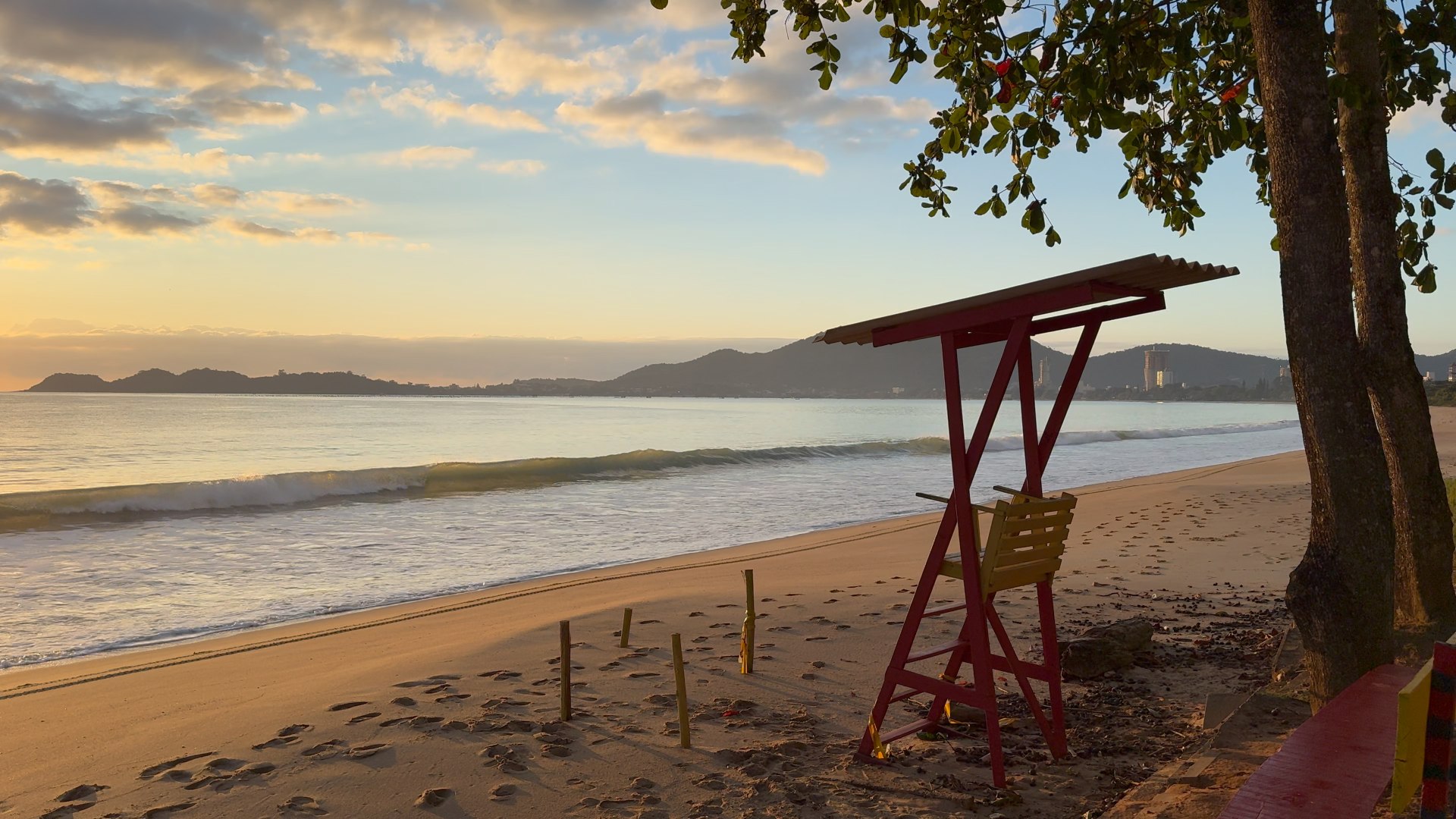 Vista da praia em frente à Souza Beach House ao entardecer, com o mar e a orla ao fundo